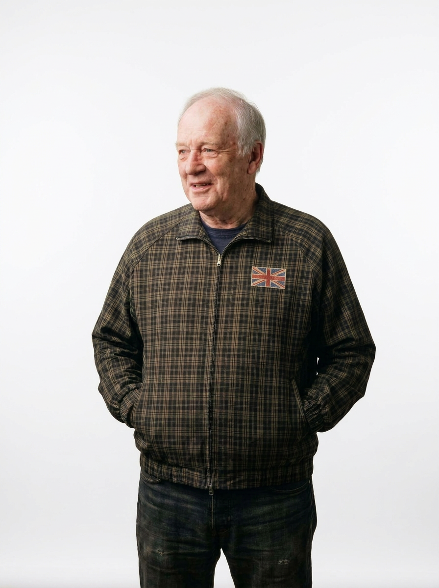 Older man wearing the check Harrington jacket zipped up, with a small faded Union Jack badge on the chest