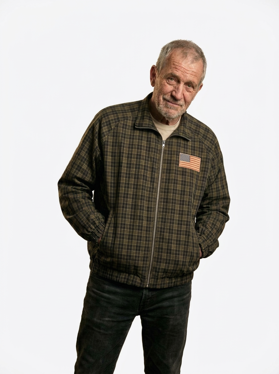 Older man wearing the check Harrington jacket zipped up, with a small faded American flag badge on the chest