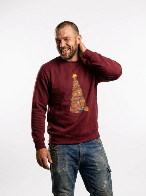 Man wearing the Brick Christmas Tree Jumper, a Christmas tree laid in brick with fairy lights, baubles and a hard hat on top