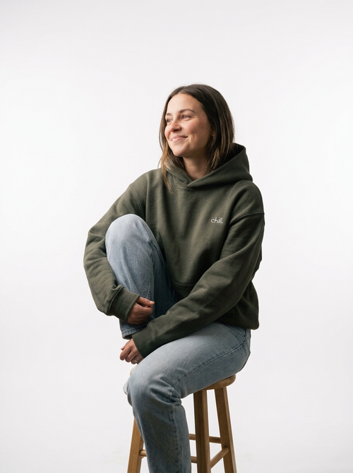 Woman sitting on a stool in the chill. embroidered boxy fleece hoodie