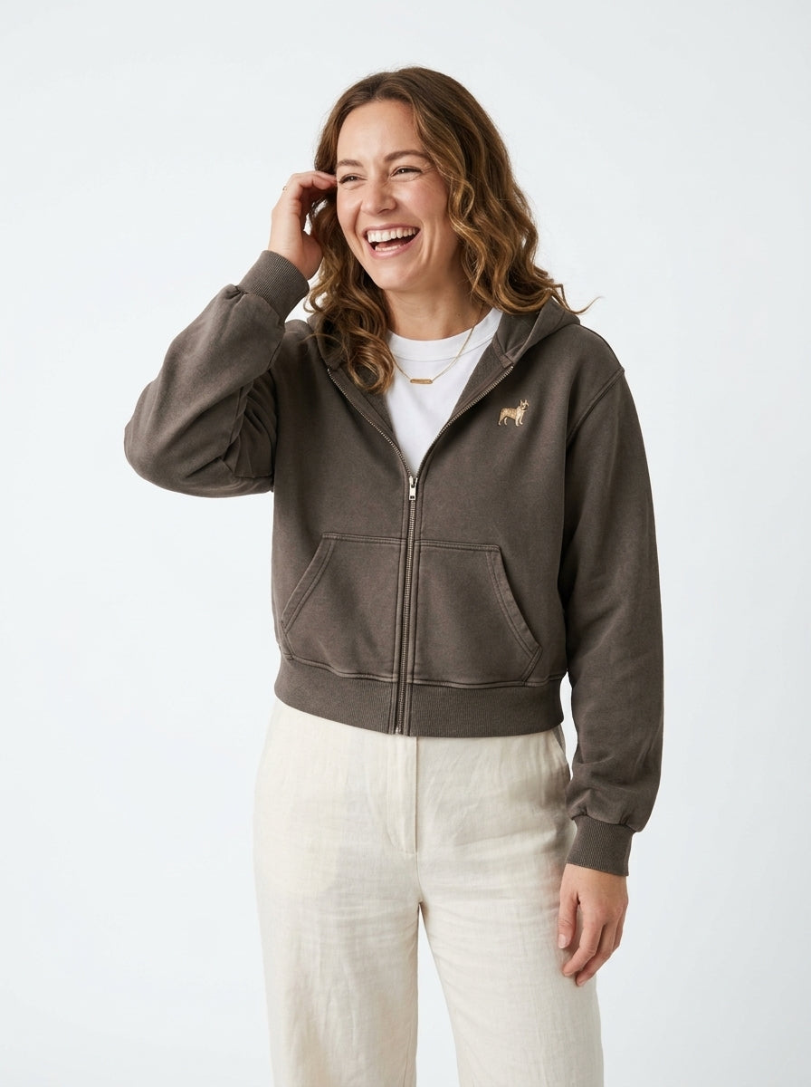 Woman laughing in the Coffee mineral wash zip hoodie with a small embroidered-look French Bulldog on the chest, worn open over a white t-shirt